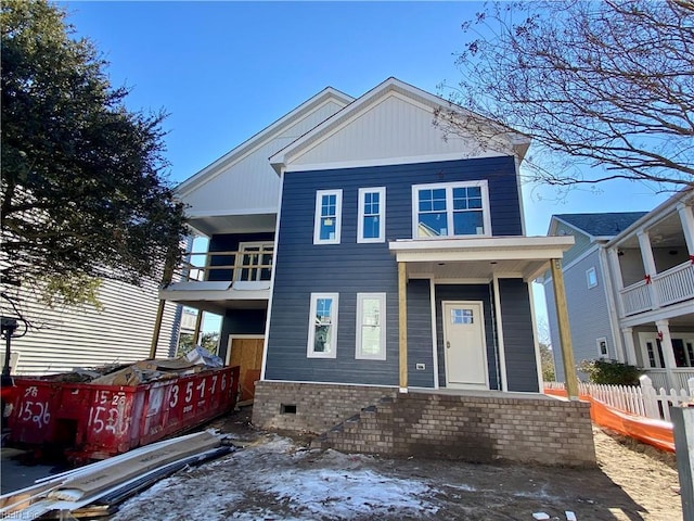 view of front of house with brick siding, fence, and a balcony