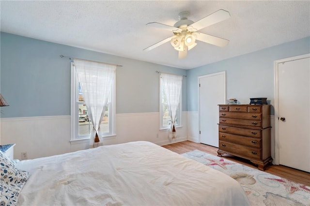 bedroom with ceiling fan, a textured ceiling, and light hardwood / wood-style flooring