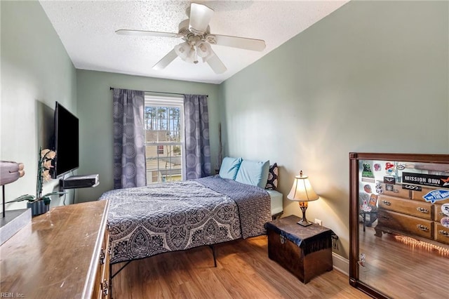 bedroom with ceiling fan, a textured ceiling, and wood-type flooring