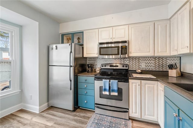 kitchen with blue cabinetry, backsplash, stainless steel appliances, and light wood-type flooring