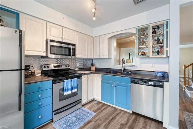 kitchen featuring hardwood / wood-style flooring, appliances with stainless steel finishes, decorative backsplash, blue cabinets, and sink