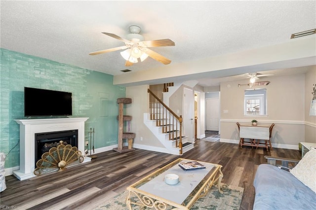 living room featuring ceiling fan, dark wood-type flooring, and a textured ceiling