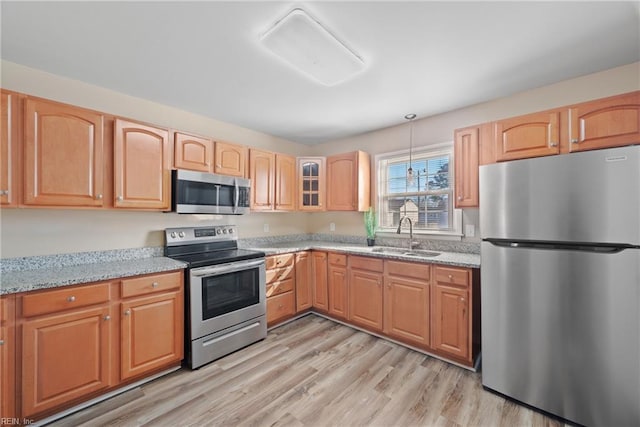 kitchen featuring sink, light stone countertops, light hardwood / wood-style floors, and appliances with stainless steel finishes