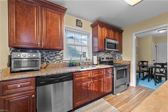 kitchen featuring backsplash, light wood-type flooring, sink, and appliances with stainless steel finishes