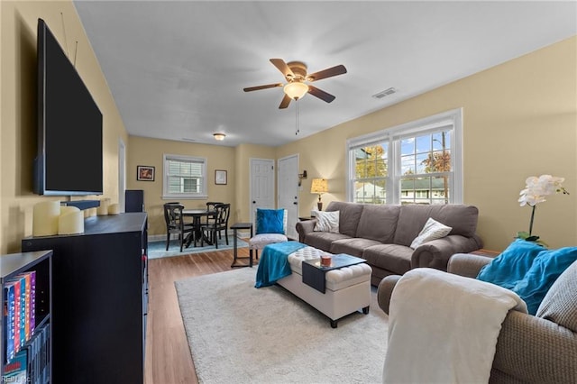 living room featuring a healthy amount of sunlight, ceiling fan, and wood-type flooring