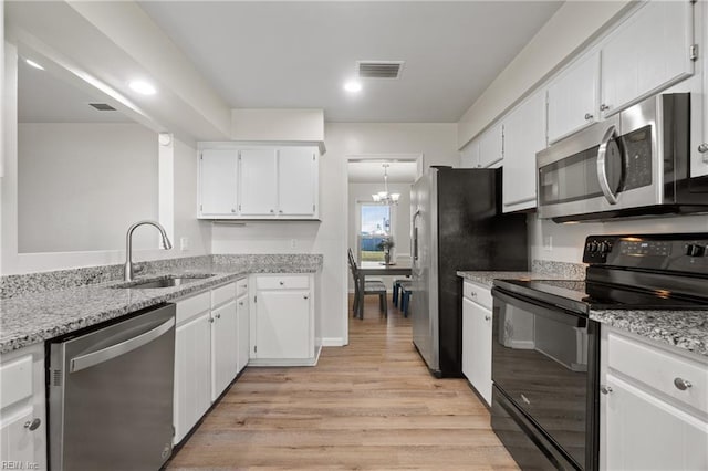 kitchen with appliances with stainless steel finishes, light stone countertops, white cabinets, an inviting chandelier, and sink