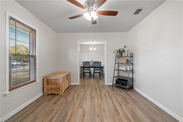 miscellaneous room with ceiling fan with notable chandelier and hardwood / wood-style floors