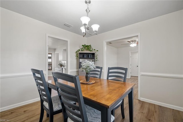 dining room featuring ceiling fan with notable chandelier and hardwood / wood-style flooring