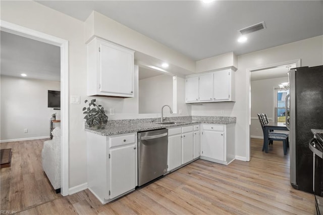 kitchen with appliances with stainless steel finishes, light hardwood / wood-style floors, light stone counters, white cabinets, and sink