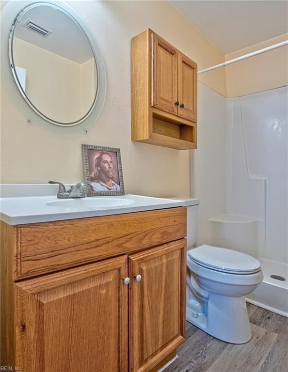 bathroom featuring hardwood / wood-style flooring, a shower, toilet, and vanity