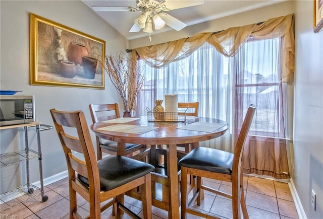 tiled dining space featuring ceiling fan and vaulted ceiling