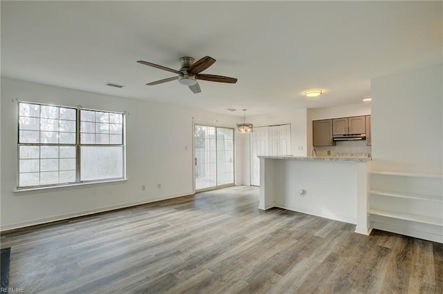 unfurnished living room featuring a ceiling fan, visible vents, and wood finished floors