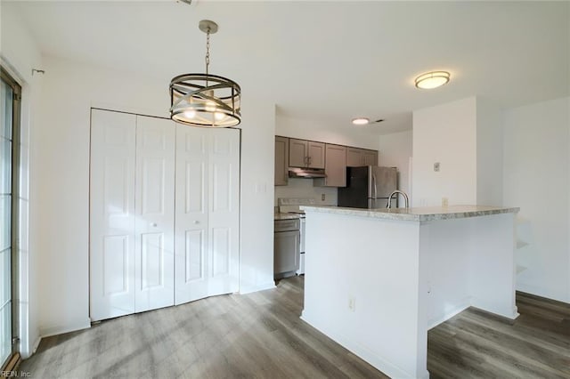 kitchen featuring pendant lighting, electric range, freestanding refrigerator, wood finished floors, and under cabinet range hood