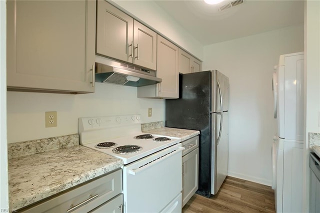 kitchen featuring white appliances, visible vents, wood finished floors, gray cabinets, and under cabinet range hood