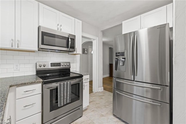 kitchen featuring dark stone countertops, white cabinetry, backsplash, and appliances with stainless steel finishes