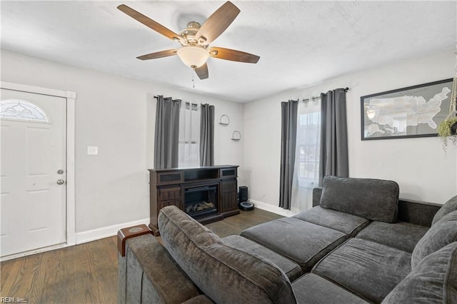 living room featuring ceiling fan, a fireplace, and dark hardwood / wood-style floors