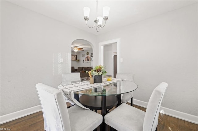 dining space with ceiling fan with notable chandelier and dark wood-type flooring