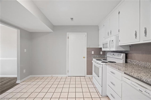 kitchen with white appliances, light stone countertops, light tile patterned floors, white cabinets, and backsplash