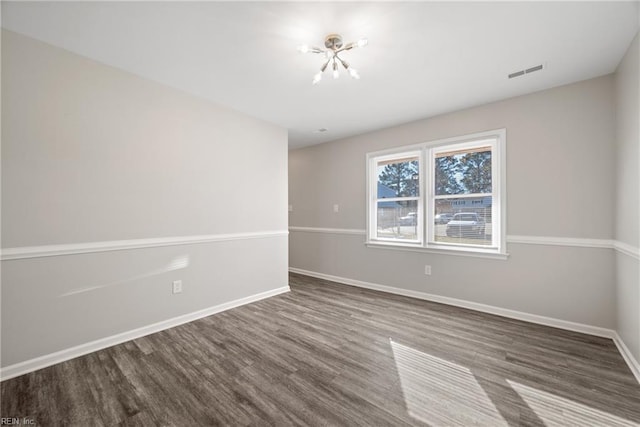 unfurnished room with a chandelier and wood-type flooring