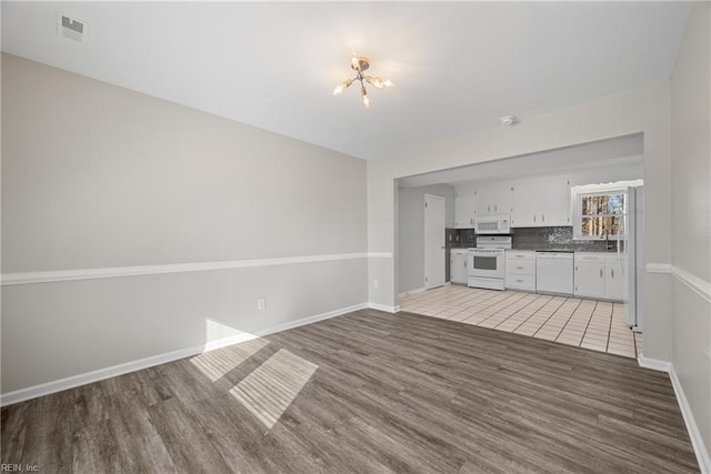 unfurnished living room with an inviting chandelier and wood-type flooring