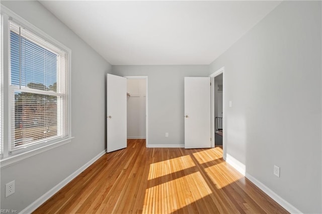 unfurnished bedroom with a walk in closet, light wood-type flooring, and a closet