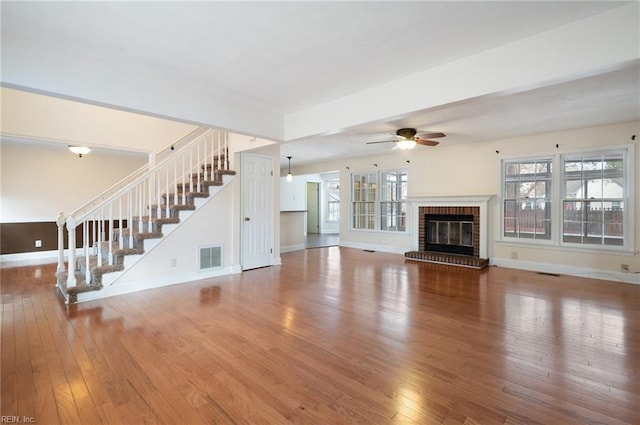 unfurnished living room featuring hardwood / wood-style flooring, a brick fireplace, plenty of natural light, and ceiling fan