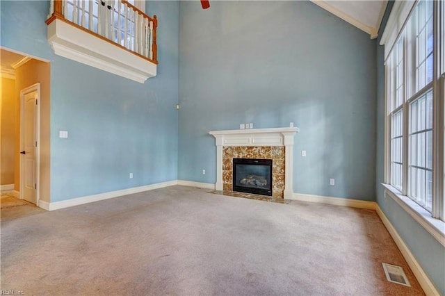 unfurnished living room with ornamental molding, a towering ceiling, and carpet