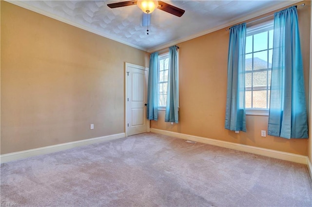 empty room featuring ceiling fan, crown molding, and carpet flooring