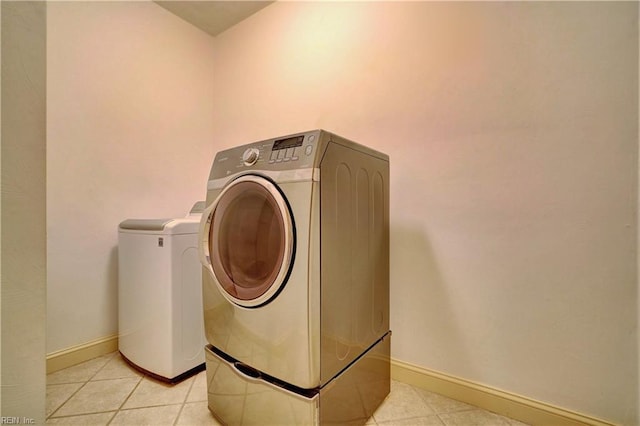 laundry area with washer and clothes dryer and light tile patterned floors