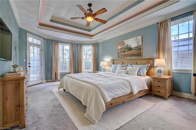 carpeted bedroom featuring access to outside, ceiling fan, a tray ceiling, and ornamental molding