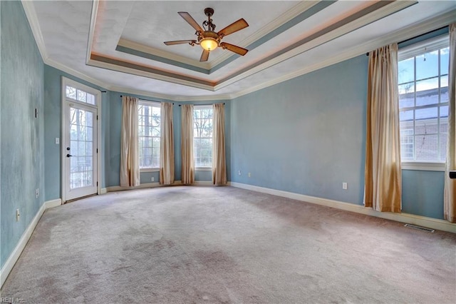 empty room featuring ceiling fan, a tray ceiling, crown molding, and light carpet