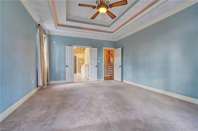 spare room featuring ceiling fan, crown molding, a raised ceiling, and light colored carpet