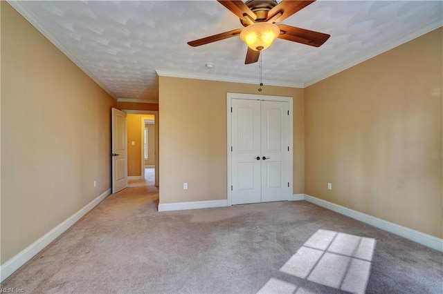 unfurnished bedroom with ornamental molding, light colored carpet, ceiling fan, and a closet