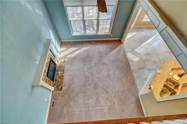 interior space featuring a high ceiling, a fireplace, and light colored carpet