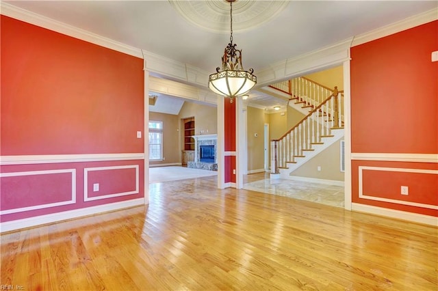 unfurnished room with lofted ceiling, wood-type flooring, and ornamental molding