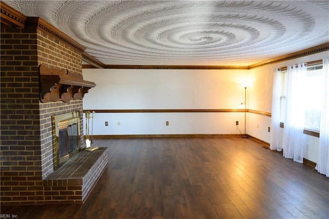 unfurnished living room featuring a brick fireplace, crown molding, and dark wood-type flooring