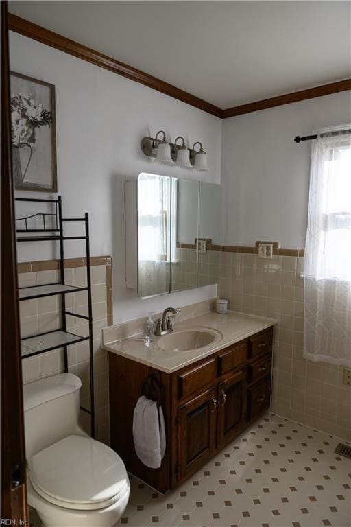 bathroom with plenty of natural light, toilet, vanity, and tile walls