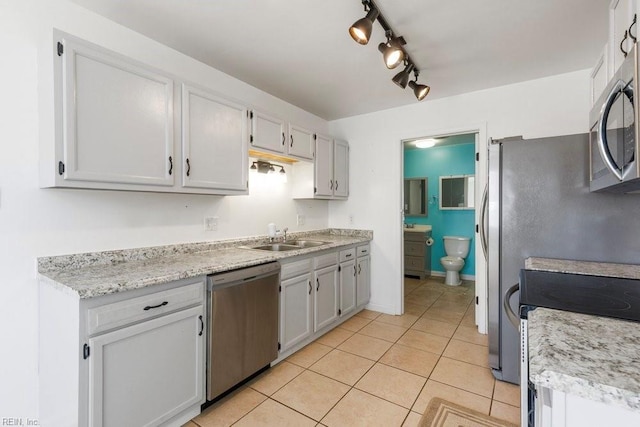 kitchen with appliances with stainless steel finishes, rail lighting, sink, and light tile patterned floors