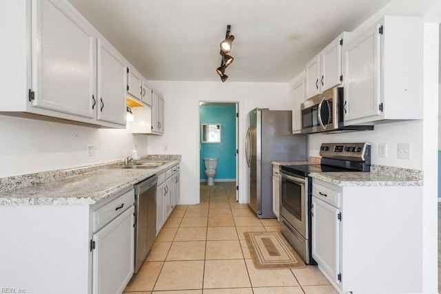 kitchen with light tile patterned flooring, appliances with stainless steel finishes, white cabinetry, rail lighting, and sink