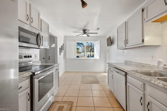 kitchen with sink, white cabinetry, light tile patterned floors, ceiling fan, and stainless steel appliances