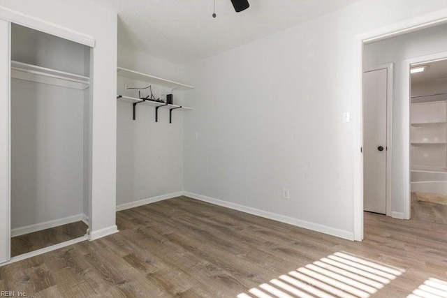 unfurnished bedroom featuring hardwood / wood-style floors, ceiling fan, and a closet