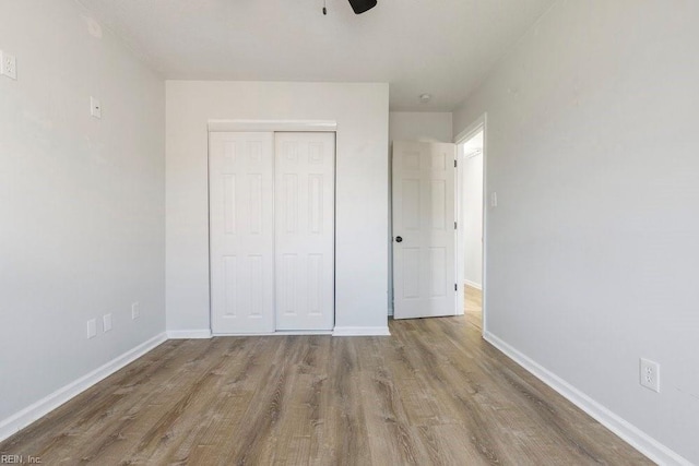 unfurnished bedroom with light hardwood / wood-style flooring, ceiling fan, and a closet