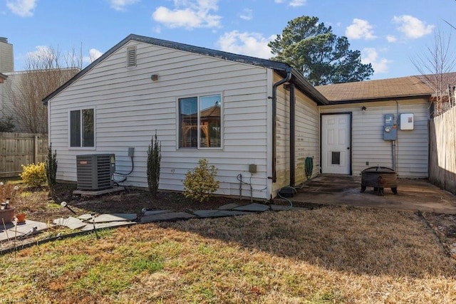 rear view of house with a patio, cooling unit, and a lawn