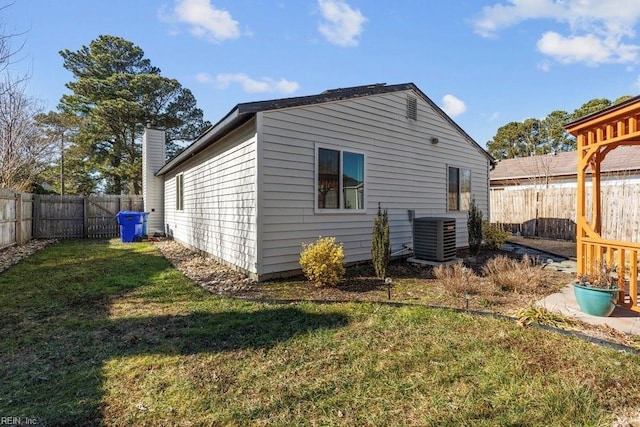 rear view of property featuring central AC and a lawn