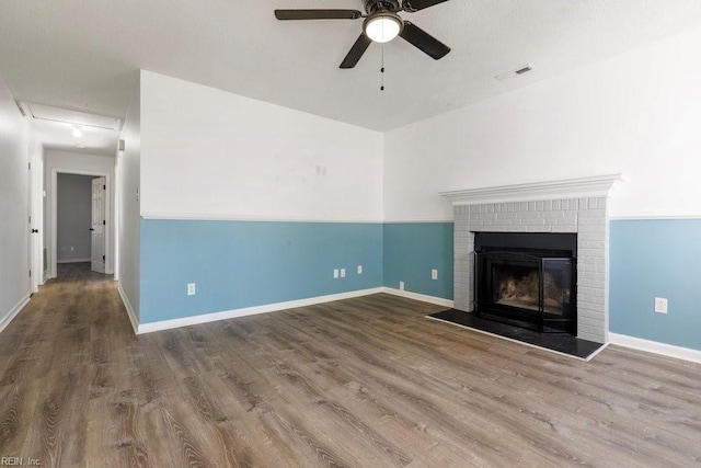 unfurnished living room featuring a brick fireplace, hardwood / wood-style floors, and ceiling fan