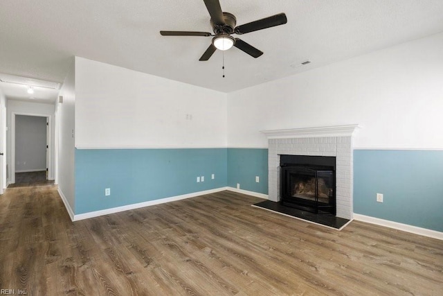 unfurnished living room with hardwood / wood-style flooring, a brick fireplace, a textured ceiling, and ceiling fan