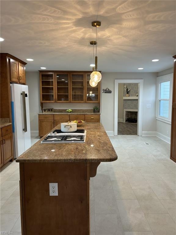 kitchen with decorative light fixtures, a fireplace, a kitchen breakfast bar, stainless steel gas cooktop, and high end fridge