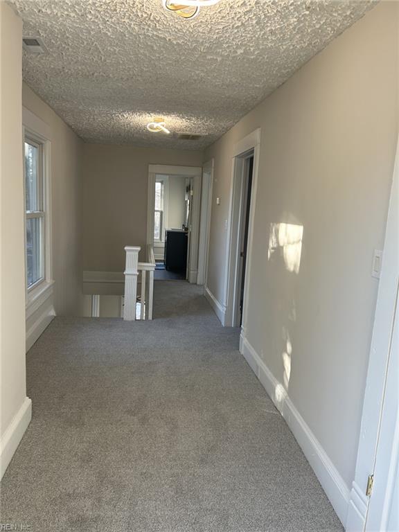 hall with a textured ceiling and carpet floors