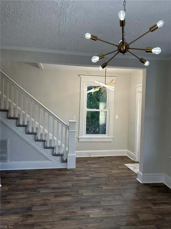 interior space featuring a textured ceiling, dark hardwood / wood-style floors, a notable chandelier, and ornamental molding