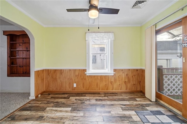 unfurnished room with ceiling fan, built in features, dark hardwood / wood-style flooring, and ornamental molding